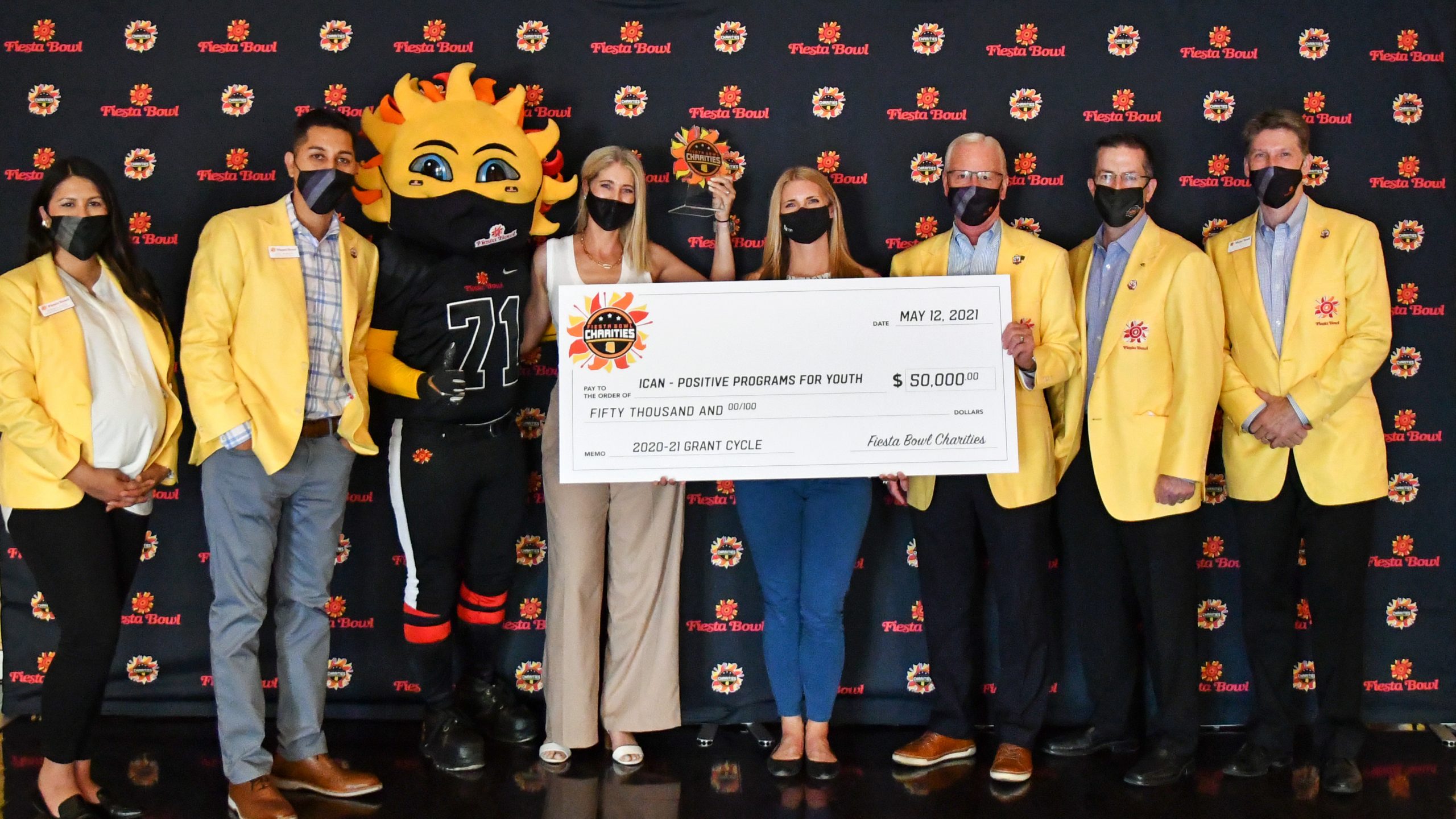 group of people in front of the suns banner with a giant check